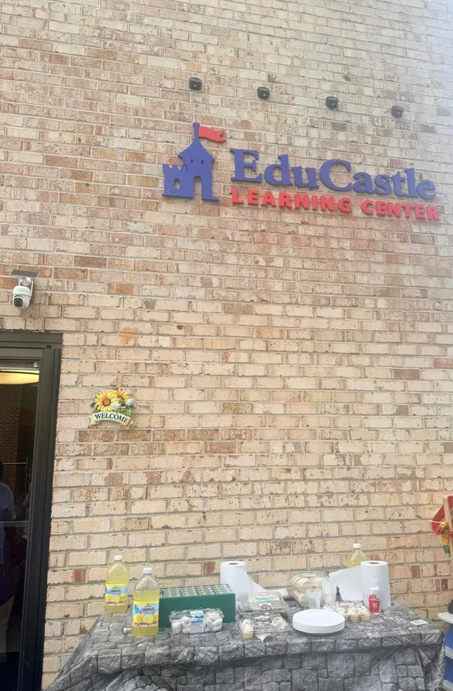 EduCastle Learning Center sign on the brick building, with a sunflower welcome plaque and an open-house snack table below
