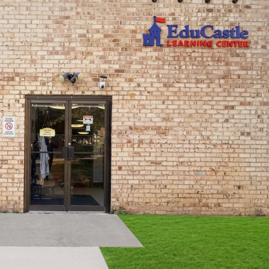 The brick front entrance of EduCastle Learning Center, with the castle logo sign above the glass double doors on Pear Tree Lane in Silver Spring, MD
