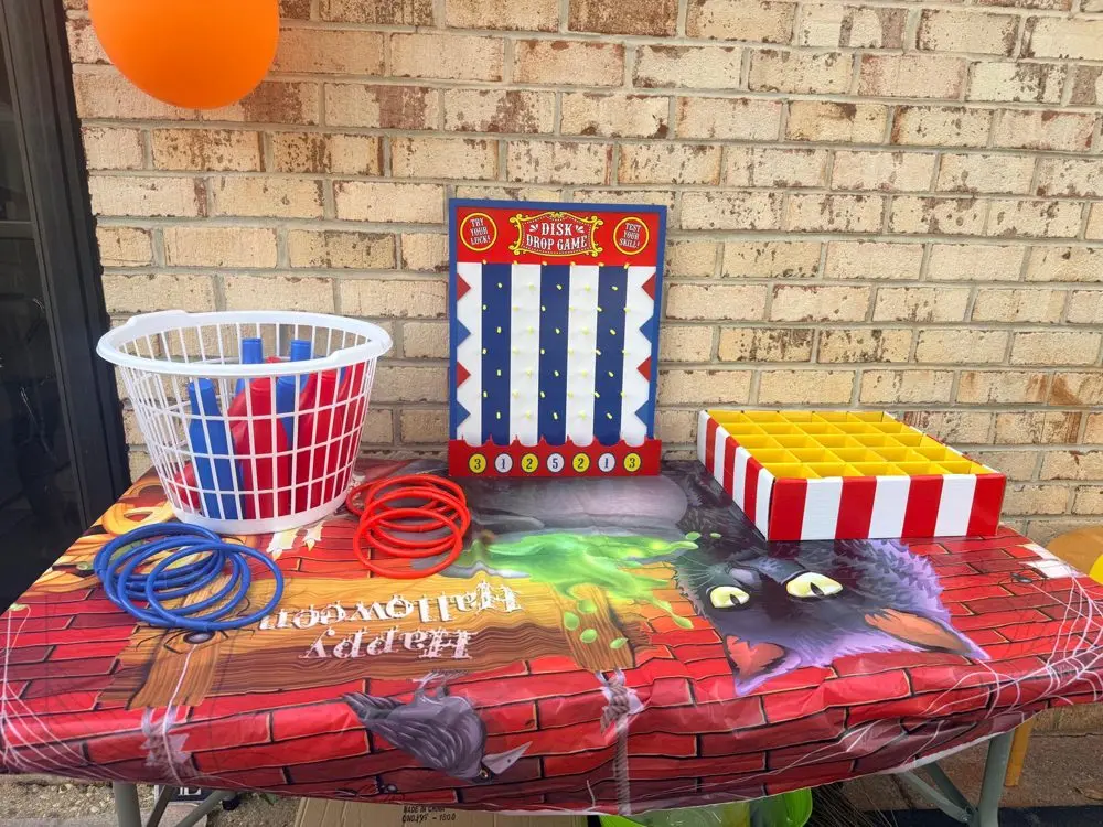 Carnival games on a Halloween tablecloth at the EduCastle fall festival: ring toss, disk drop game and bowling pins