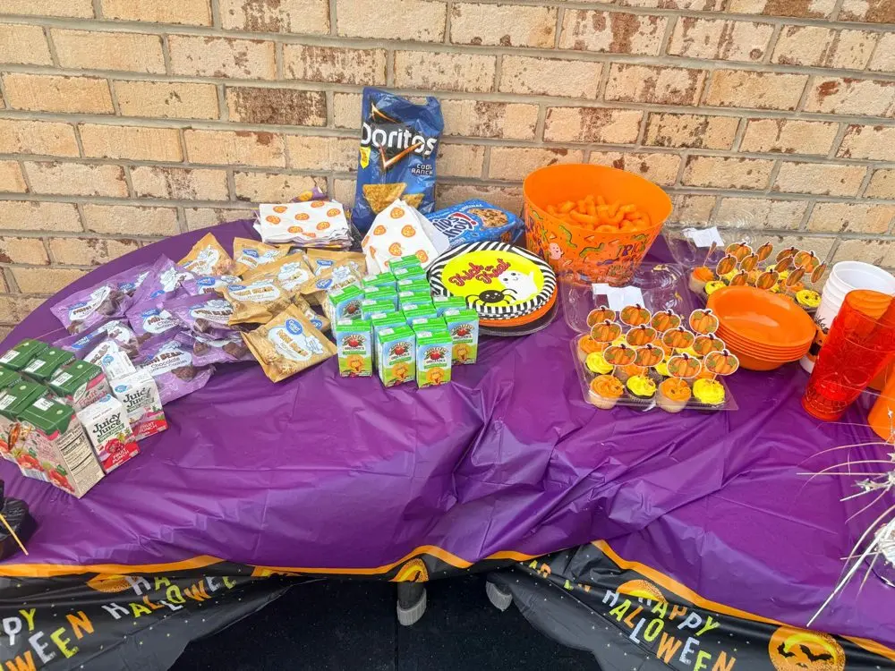 Halloween treats table at EduCastle with pumpkin cupcakes, snacks and juice boxes on a purple tablecloth