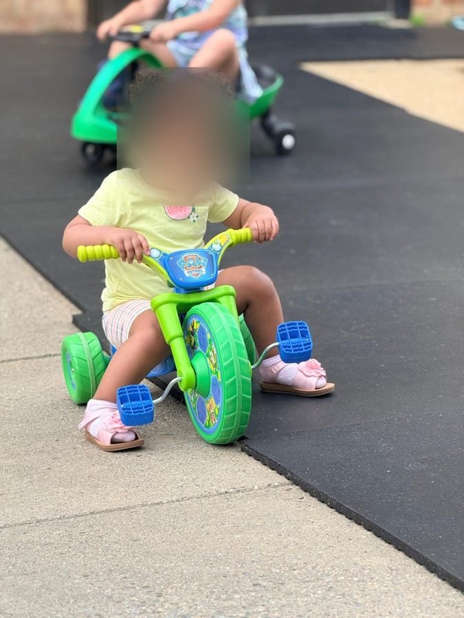 Full speed on the trike at EduCastle Learning Center, faces blurred for privacy