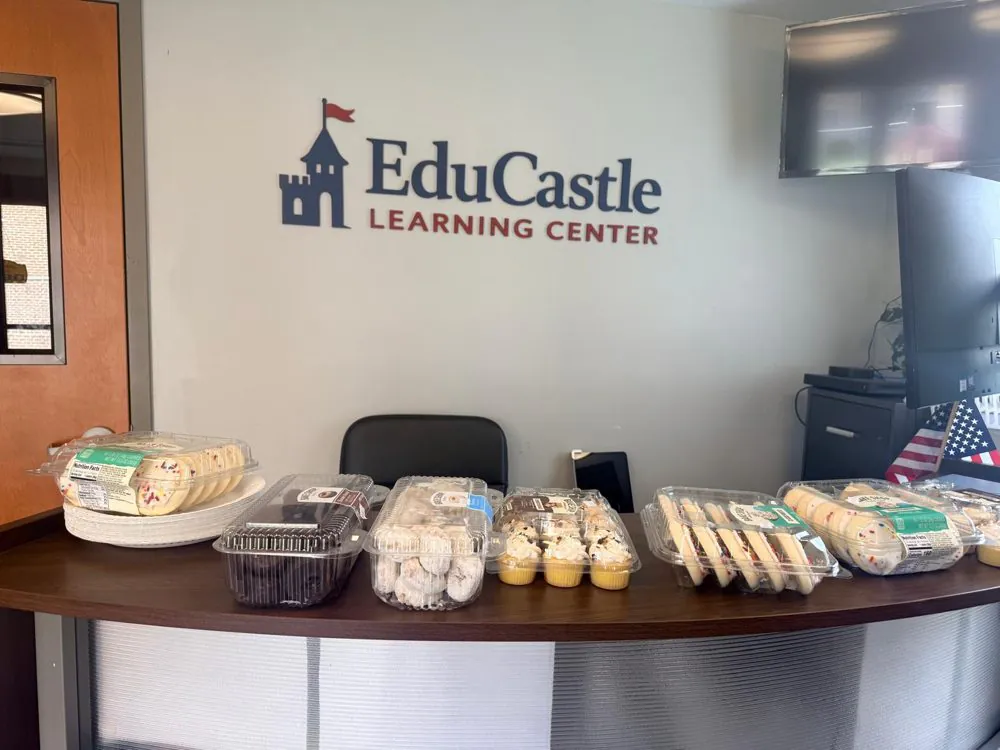 Cookies, cupcakes and donuts set out on the EduCastle front desk beneath the logo for the open house