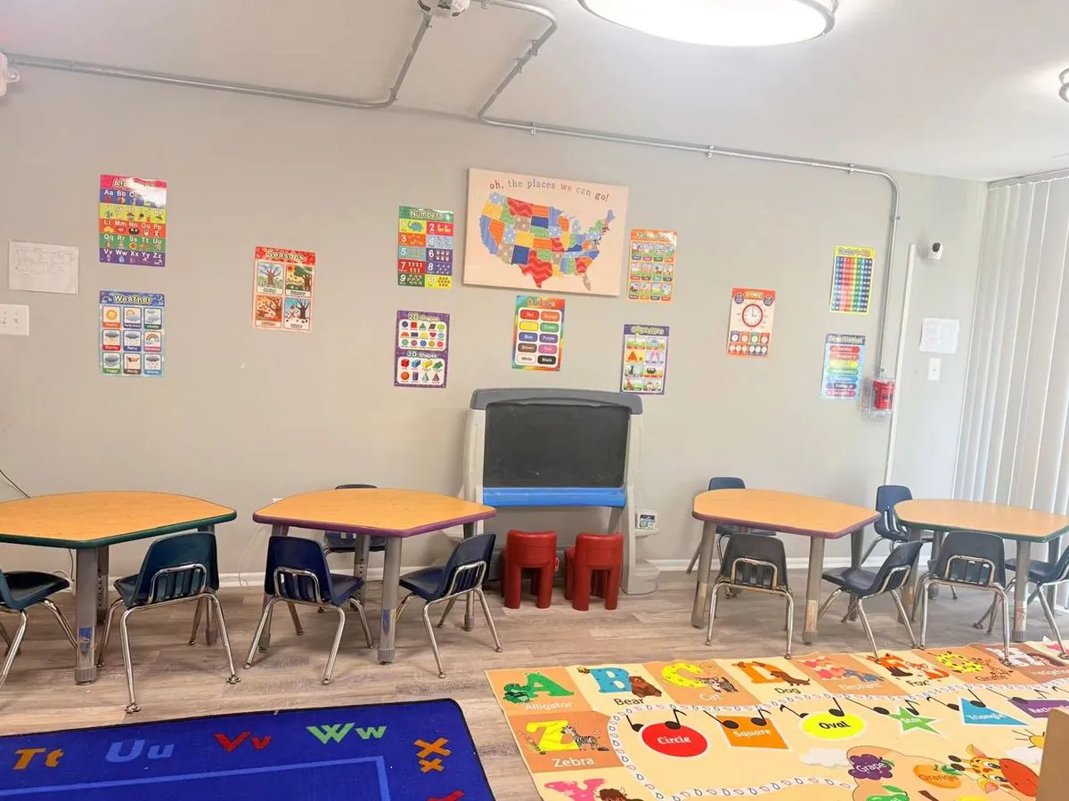 School-age room at EduCastle with group tables, a chalkboard and a United States map among learning posters